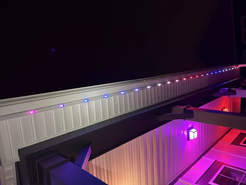 Close-up of permanent RGB LED trim lighting by Light DMV — individually-addressable chips along the soffit running a red, white & blue program