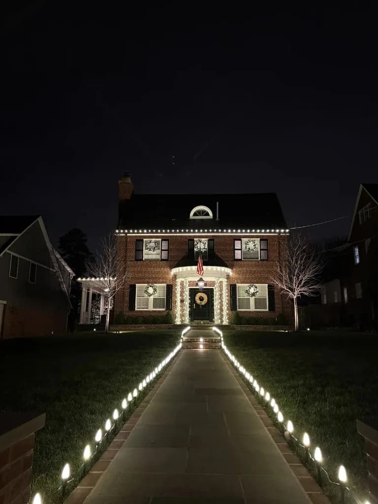 Christmas light installation in the DMV by Light DMV — warm white accents on a brick home with lit pathway