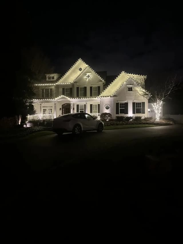 Christmas light installation in the DMV by Light DMV — warm white roofline and wreath on a stone-front home