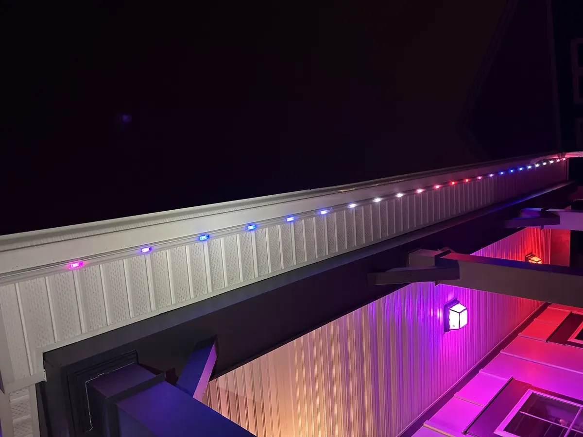 Close-up of permanent RGB LED trim lighting by Light DMV — individually-addressable chips along the soffit running a red, white & blue program