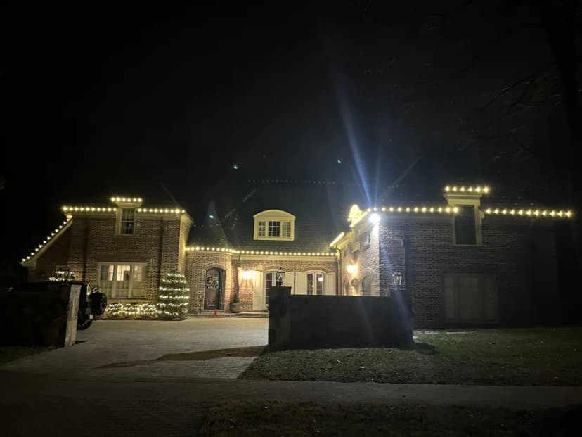 Sprawling C9 warm-white roofline across every gable and dormer of a large brick Potomac colonial — luxury estate Christmas light installation by Light DMV in Avenel-style architecture