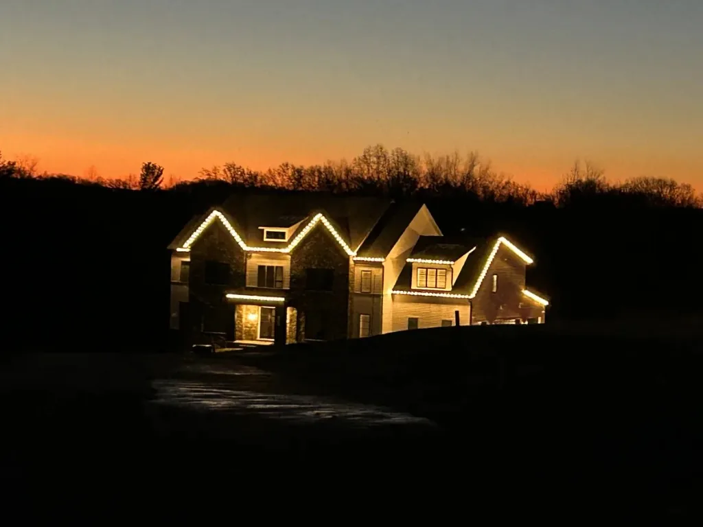 Christmas light installation in the DMV — warm white roofline at dusk on a custom home